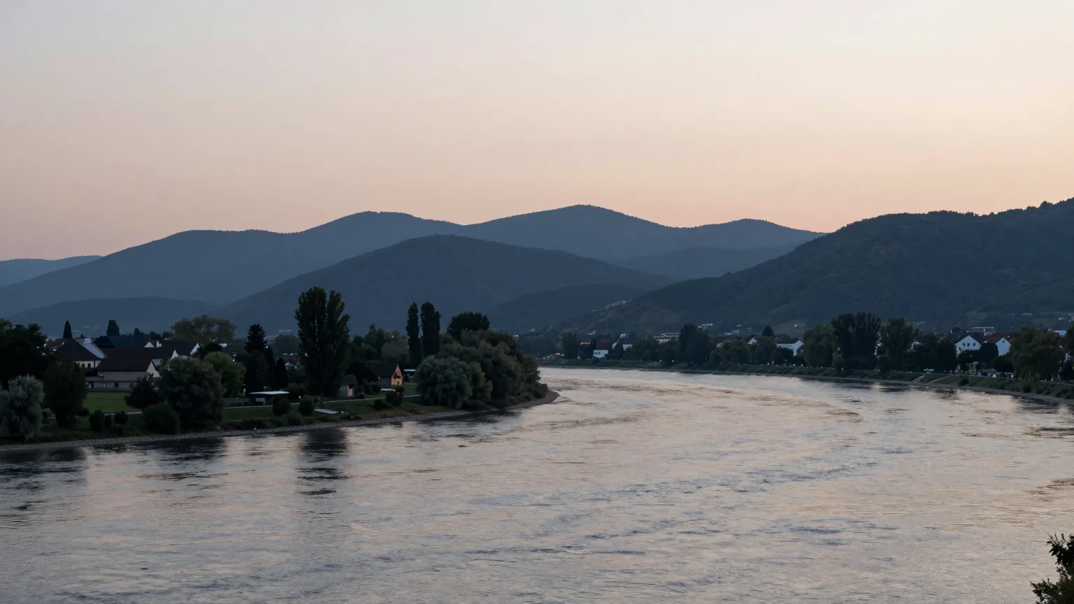 Breiter Fluss in der Abenddämmerung, bewaldete Hügel am Ufer